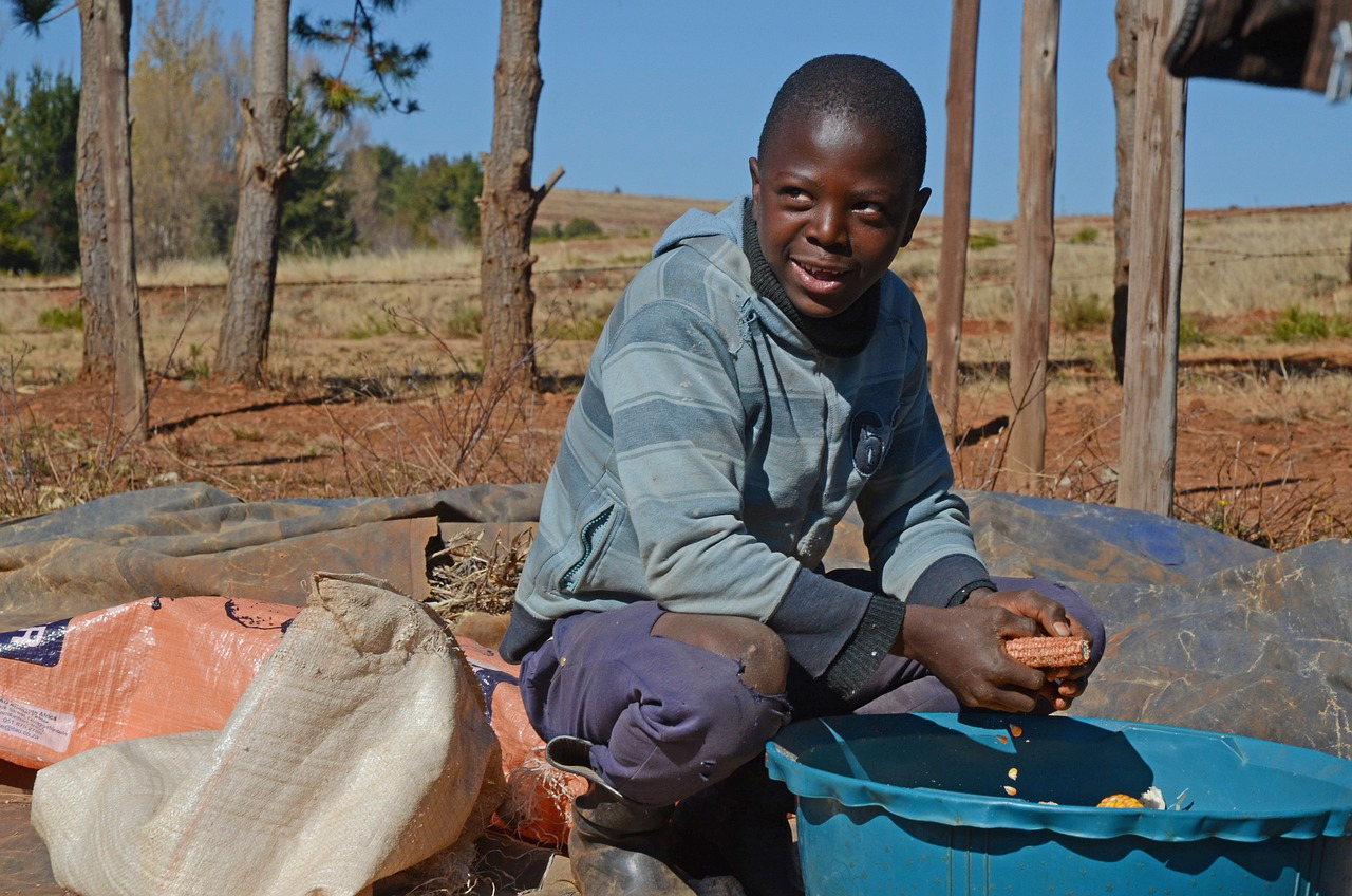 Young man in South Sudan shelling maize into a bowl